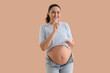 © Pixel-Shot - Pregnant woman brushing teeth on beige background