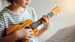 © CreativeArt - Child learning to play ukulele, hands on strings, following sheet music during music lesson and education