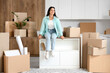 © Pixel-Shot - Beautiful woman with cardboard boxes sitting in kitchen on moving day