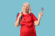 © Pixel-Shot - Mature female plumber with pipes and wrench on blue background