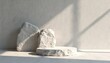 © Pete - Minimalist scene with rough stone podium, rocks on light gray concrete wall background. Soft shadows from sunlight create natural, organic, spa ambiance. Stone platform suitable for product display,