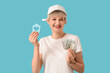 © Pixel-Shot - Portrait of beautiful young woman with house model and money on blue background. Mortgage concept