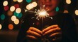 © JUST PURE PHOTOS - Person holding sparkler in hands with festive lights in the background at night