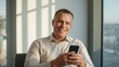 © Provisualassets - A middle-aged man smiling while using his smartphone in a modern office with a city view
