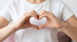 © ATFStock - A person forming a heart shape with their hands, symbolizing love, care, and affection, with a white t-shirt and a blurred background, conveying a sense of tenderness and warmth.