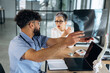 © standret - Male healthcare professional in blue shirt discusses X-ray results with female patient in a modern office setting, laptop and anatomical model visible on the table