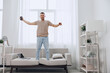 © SHOTPRIME STUDIO - Happy man celebrating his digital detox journey, embracing work-life balance with joy, while practicing self-care in a cozy living space.