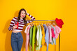 © deagreez - Young woman shopping smiling with colorful clothes on a rack against a bright yellow background fashion lifestyle portrait