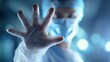 © Image - A medical professional in protective gear holds up their hand in a warning gesture.