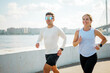 © muse studio - People run near a river and city skyline during sunny weather in the afternoon