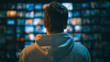 © Daria - Person in casual hoodie watching multiple digital screens displaying various blurred images in a dimly lit room showing a modern media control environment