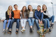 © anatoliycherkas - Group of diverse teenagers sitting together at skatepark, smiling at camera, embracing friendship and youth culture