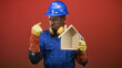 © Krakenimages.com - Man builder in blue hardhat holds wooden house model and points finger to head while wearing gloves in studio; safety concern.