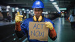 © Krakenimages.com - Man construction worker holds cardboard sign reading act now and points with gloved hand in building; urgency.
