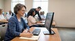 © Philipp - Senior woman using desktop computer in classroom learning digital skills