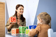 © littlewolf1989 - Speech therapist teaching child communication skills using alphabet blocks during an educational session, helping with speech and language development in a clinic