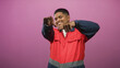 © Krakenimages.com - Man pointing both hands toward camera in a pink studio, wearing red work uniform and smiling broadly; joy playful.