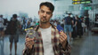 © Krakenimages.com - Young hispanic man holding credit card and miniature shopping cart at crowded airport terminal representing online shopping and consumerism concept in busy travel setting.