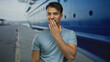 © Krakenimages.com - Young man with hand over mouth standing at port beside large cruise ship, wearing casual blue shirt, evoking surprise outdoors at a seaside location.