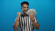 © Krakenimages.com - Young hispanic man referee holding cash dollars over isolated blue background shows excitement and success.