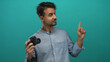© Krakenimages.com - Young hispanic man holding camera pointing at something on isolated green background suggesting idea or direction