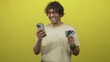 © Krakenimages.com - Man holding smartphone and creditcard in studio, smiling and wearing glasses and a casual tshirt while showing cards; happiness trust.
