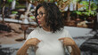 © Krakenimages.com - Middle age hispanic woman points finger to chest in vibrant green park; self awareness confidence identity.
