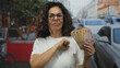 © Krakenimages.com - Middle aged hispanic woman extends her fist forward to camera on busy street holding mexican pesos and banknotes; assertiveness empowerment.