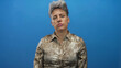 © Krakenimages.com - Caucasian woman with short gray hair wearing snake print blouse rolls eyes in solid blue studio; disgust.