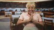 © Krakenimages.com - Woman pointing to her chest with hands in a restaurant dining room, expressive face and eyeglasses, bracelets and necklace visible while speaking to camera; joyful confidence.