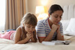 © New Africa - Mother and her daughter with Bible praying on bed at home