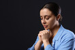 © New Africa - Woman praying on black background, space for text
