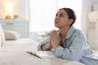 © New Africa - Religion. Woman with Bible praying at home, space for text