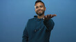 © Krakenimages.com - Man smiling and extending hand toward camera in blue studio wearing hoodie with visible hand and beard; welcoming.