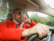 © mark_gusev - A man in his 50s an is driving a car and wearing sunglasses. He is smiling and he is enjoying the ride. Positive male model in red travel jacket behind driver wheel and with safety belt.