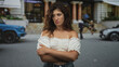 © Krakenimages.com - Woman with arms crossed showing bare shoulders on a city street in front of building steps; annoyance.
