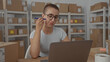 © Krakenimages.com - Woman holding pen to cheek while checking laptop in a building workspace; concentration planning productivity.