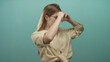 © Krakenimages.com - Young blonde woman makes binoculars gesture in studio with teal background; exploration curiosity playfulness.