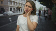 © Krakenimages.com - Middleaged blonde woman in white shirt with hand on cheek for toothache on city street lined with buildings; discomfort.