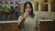 © Krakenimages.com - Woman points finger toward camera with hand in old town building courtyard wearing an apron and short sleeve shirt outdoors; confidence empowerment.