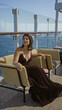 © Krakenimages.com - Woman sitting on wicker chair, hand on armrest, exposed cleavage and relaxed posture on cruise terrace building; serenity vacation.