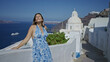 © Krakenimages.com - Woman with bare shoulder and raised arm on santorini street by white church, eyes closed and head tilted back; serenity.