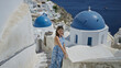 © Krakenimages.com - Woman with bare back touching railing and looking toward blue church dome on building stairs in santorini; serenity.