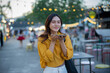 © Laingzaifa - An Asian woman is strolling through a night market, enjoying traditional street food, colorful lanterns, and smiling at the bustling city stalls. It's a vibrant atmosphere and a wonderful cultural