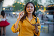 © Laingzaifa - An Asian woman is strolling through a night market, enjoying traditional street food, colorful lanterns, and smiling at the bustling city stalls. It's a vibrant atmosphere and a wonderful cultural