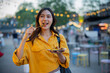 © Laingzaifa - An Asian woman is strolling through a night market, enjoying traditional street food, colorful lanterns, and smiling at the bustling city stalls. It's a vibrant atmosphere and a wonderful cultural