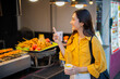© Laingzaifa - An Asian woman is strolling through a night market, enjoying traditional street food, colorful lanterns, and smiling at the bustling city stalls. It's a vibrant atmosphere and a wonderful