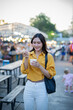 © Laingzaifa - Asian women enjoy delicious street food at night markets, smiling throughout their vacation, exploring the city's culture, vibrant lights, and fun-filled adventures.