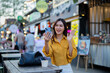 © Laingzaifa - Asian women enjoy delicious street food at night markets, smiling throughout their vacation, exploring the city's culture, vibrant lights, and fun-filled adventures.