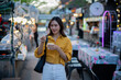 © Laingzaifa - Asian women enjoy delicious street food at night markets, smiling throughout their vacation, exploring the city's culture, vibrant lights, and fun-filled adventures.